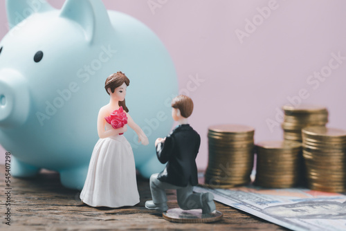 Save money for wedding and planning wedding concept. Sustainable financial goal for family life or married life. Miniature wedding on rows of rising coins, depicts savings or growth for new family. photo