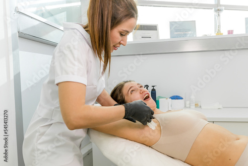 Girl on the procedure of depilation of hair removal from the armpit, pain from wax hair removal photo