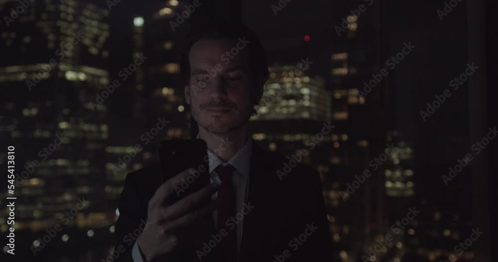 Businessman using Smart phone Working Late in Office with City Skyline Businessman using Smart phone Working Late in Office with City Skyline