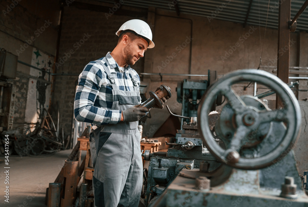 Metal processing. Factory male worker in uniform is indoors Metal processing. Factory male worker in uniform is indoors