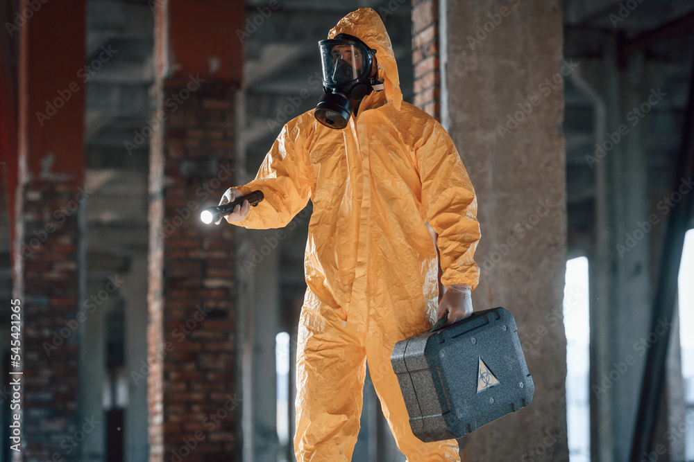 Man dressed in chemical protection suit in the ruins of the post apocalyptic building Man dressed in chemical protection suit in the ruins of the post apocalyptic building