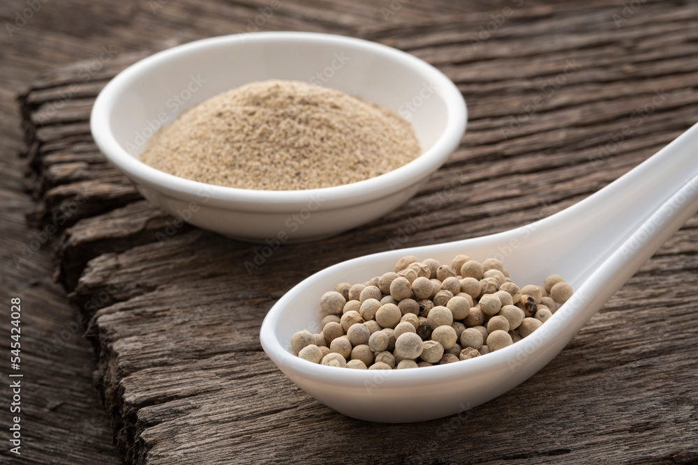 whole white peppercorns on spoon on wood table whole white peppercorns on spoon on wood table