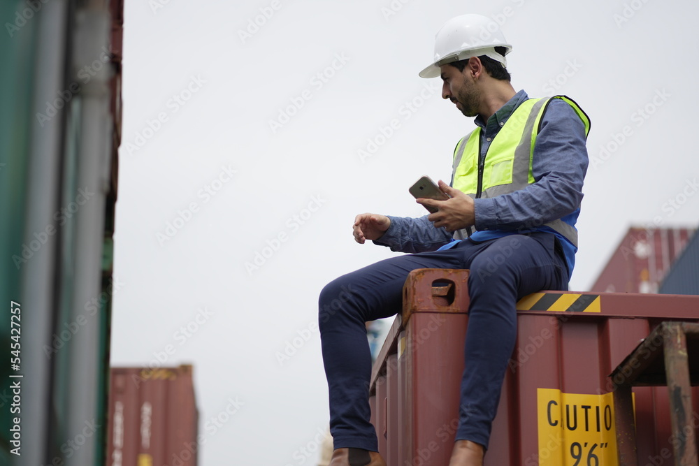 Dock worker man in safety vest work in container port terminal. male Industrial Engineer in Hard Hat, High-Visibility Vest Working. Inspector or Safety Supervisor in Container Terminal. shipping yard.