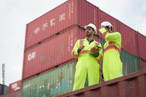 Dock worker man in safety vest work in container port terminal. male Industrial Engineer in Hard Hat, High-Visibility Vest Working. Inspector or Safety Supervisor in Container Terminal. shipping yard.
