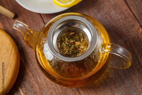 teapot of lemongrass tea on a wooden table set for tea drinking.