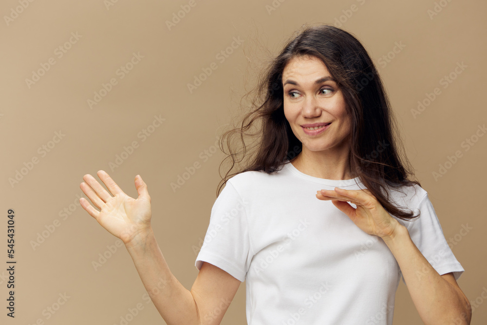 portrait of a sweet, beautiful, charming, pleasant woman with black hair, blowing in the wind, in a white T-shirt. Studio photo on a plain background portrait of a sweet, beautiful, charming, pleasant woman with black hair, blowing in the wind, in a white T-shirt. Studio photo on a plain background