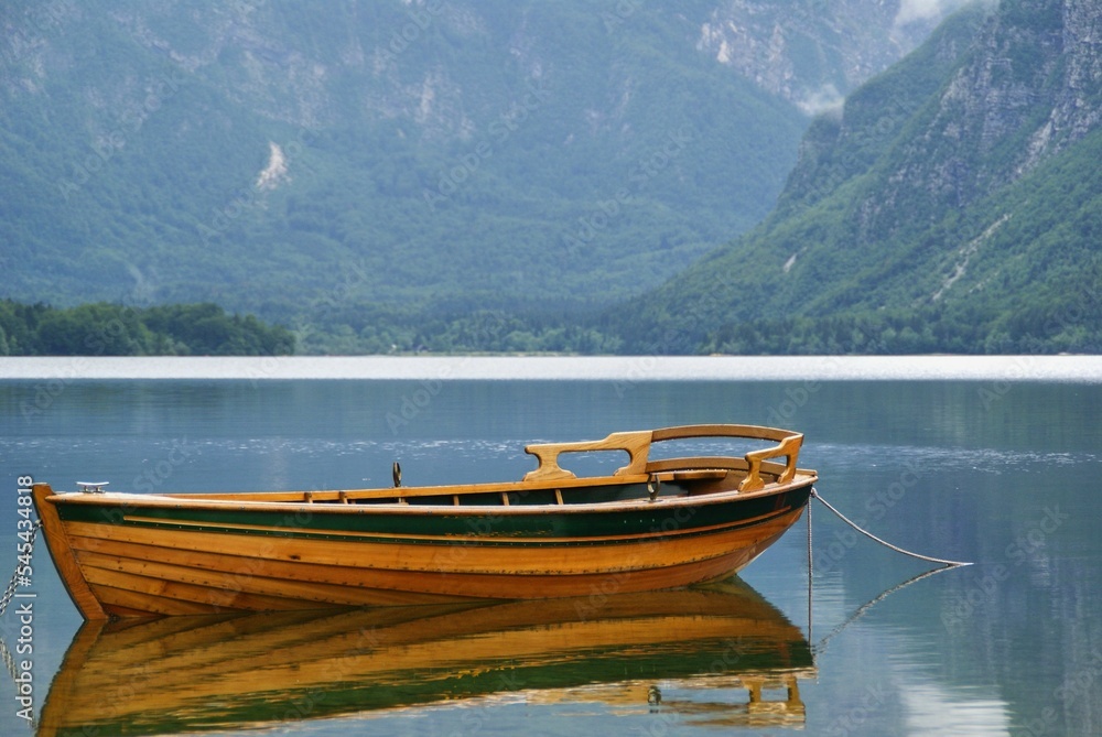 Scenic view of a boat in Lake Bohinj surrounded by green mountains in Slovenia
