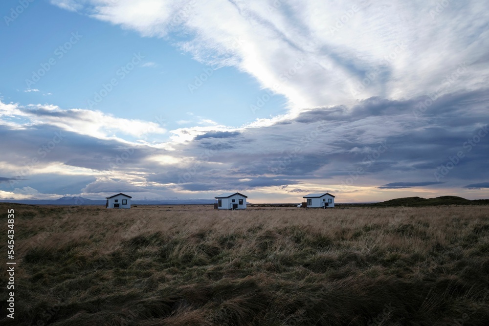 Village with white houses in front of a field with a cloudy sky in the background
