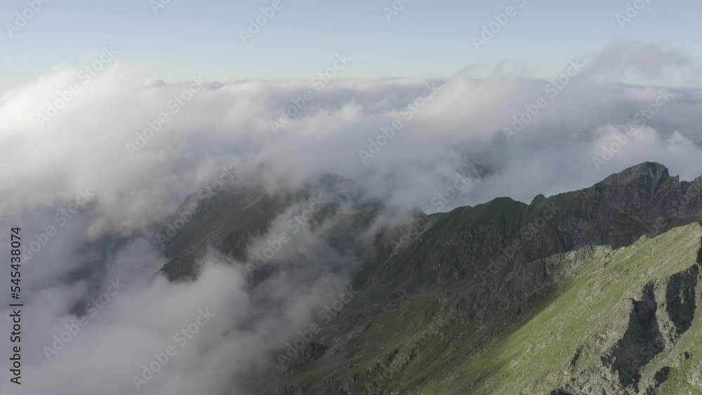 Aerial slow movement around greenery mountains under blue bright sky Aerial slow movement around greenery mountains under blue bright sky