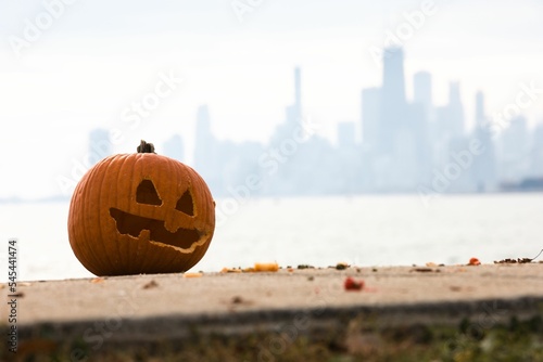 Closeup shot of a carved pumpkin on the floor with the Chicago cityscape in the background