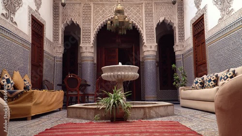 Interior footage of a traditional Moroccan Riad. Courtyard of Riad with fountain, furniture and ornate carvings and tiles. photo