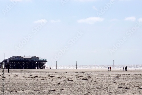 An der Nordsee Bild mit hellen Farben Gebäude am linken Bildrand vereinzelte Menschen am Strand Blick vom Strand zum Meer  photo