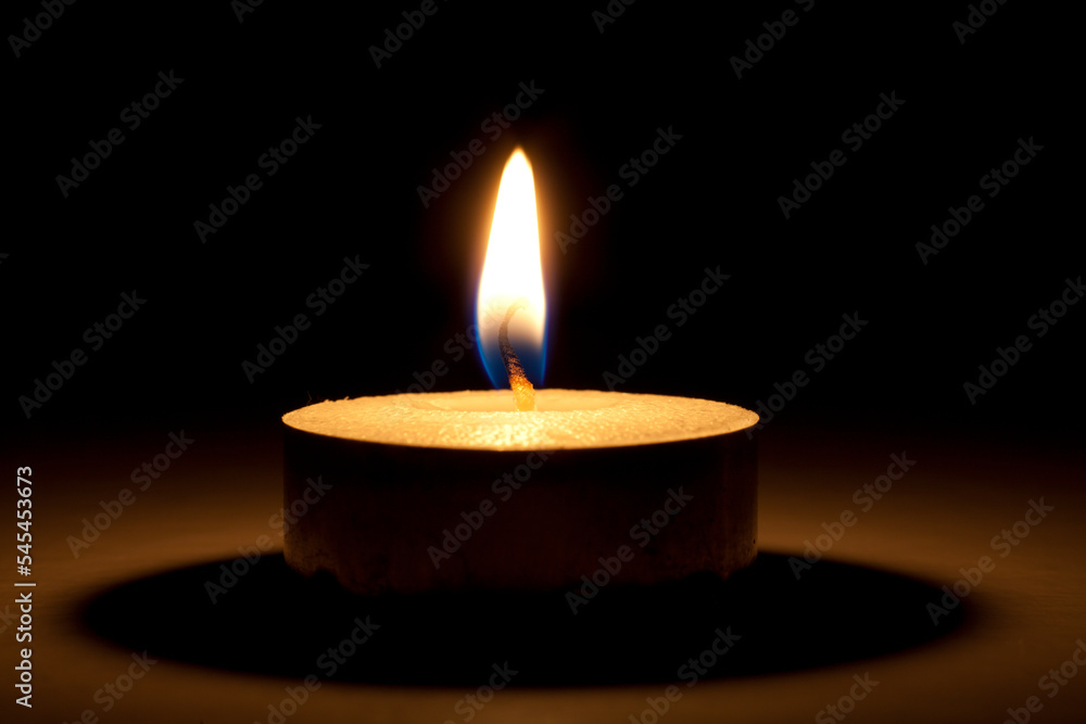 single burning warm candle or tealight close-up in the dark single burning warm candle or tealight close-up in the dark