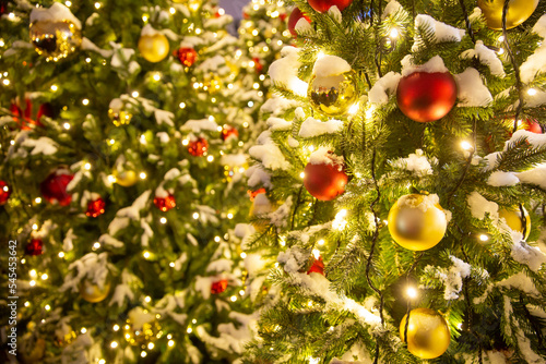 christmas decorations in city square. close up image of illuminated christmass trees with garlands, fairy lights and balls on defocused background