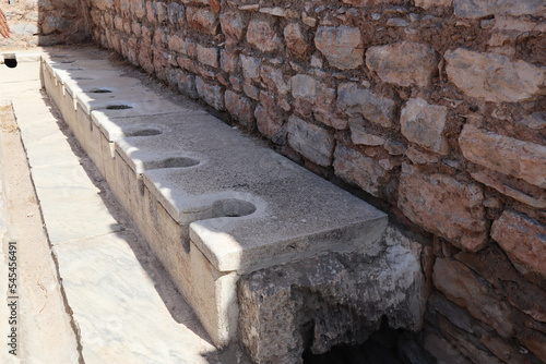 Ancient public Toilet bathroom seats on Ephesus made of rocks, bricks, granite and marble photo