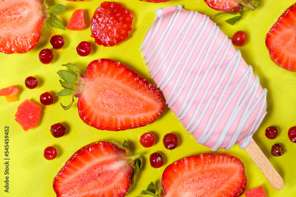 Pink ice cream on a stick with strawberries and red lingonberries on a yellow background. Pink ice cream on a stick with strawberries and red lingonberries on a yellow background.