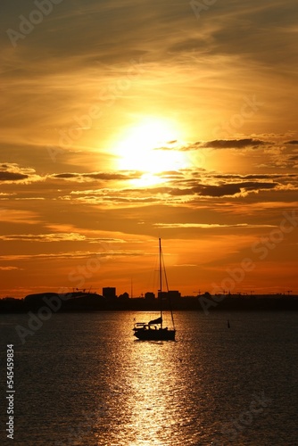 Vertical sunset view of Dublin bay, Ireland with light reflecting in the water with a boat