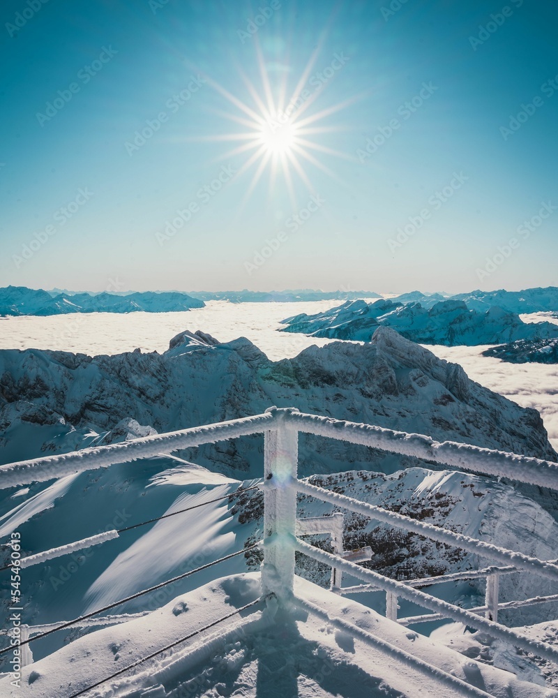 Vertical shot of frozen railings overlooking a vast winter landscape - obrazy, fototapety, plakaty 