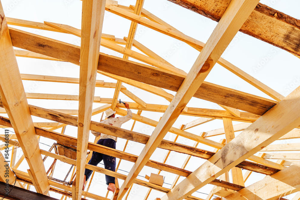 Construction of a wooden frame roof. A carpenter connects the details of a large structure. Unrecognizable person. selective focus