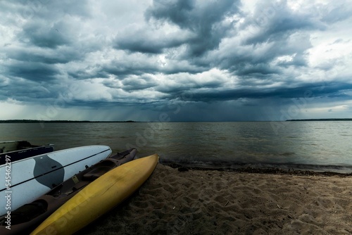 Surfboards on the beach against calm sea and cloudy sky