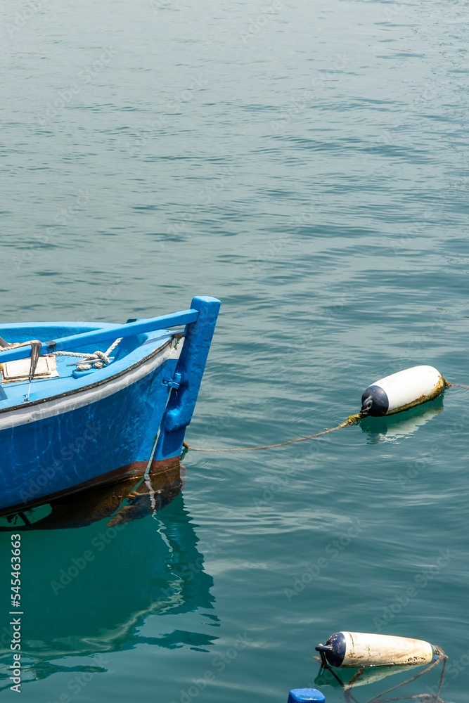 Shot of a blue classic fishing boat hanging in the dark turquoise water at the harbor