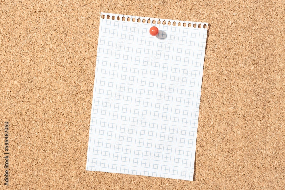 Blank grid paper sheet pinned on cork board Blank grid paper sheet pinned on cork board