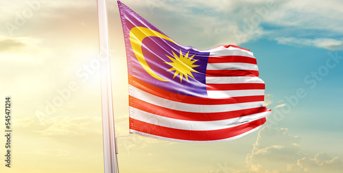 Waving Flag of Malaysia in Blue Sky. The symbol of the state on wavy cotton fabric.