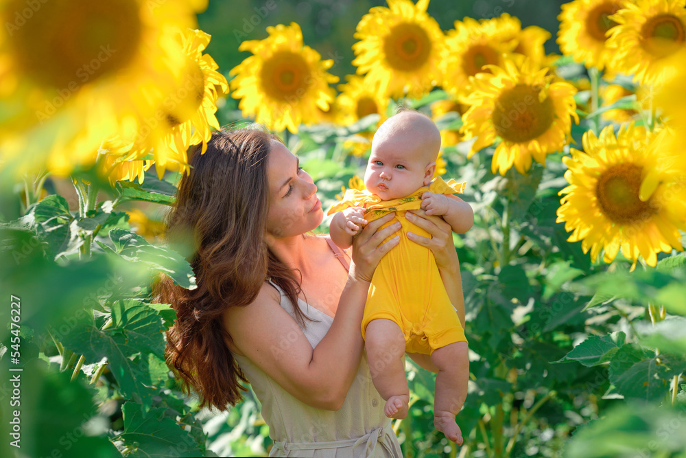 Young mother and baby girl happy together, hugging in nature in a field of yellow sunflowers. Concept of a happy family life Young mother and baby girl happy together, hugging in nature in a field of yellow sunflowers. Concept of a happy family life