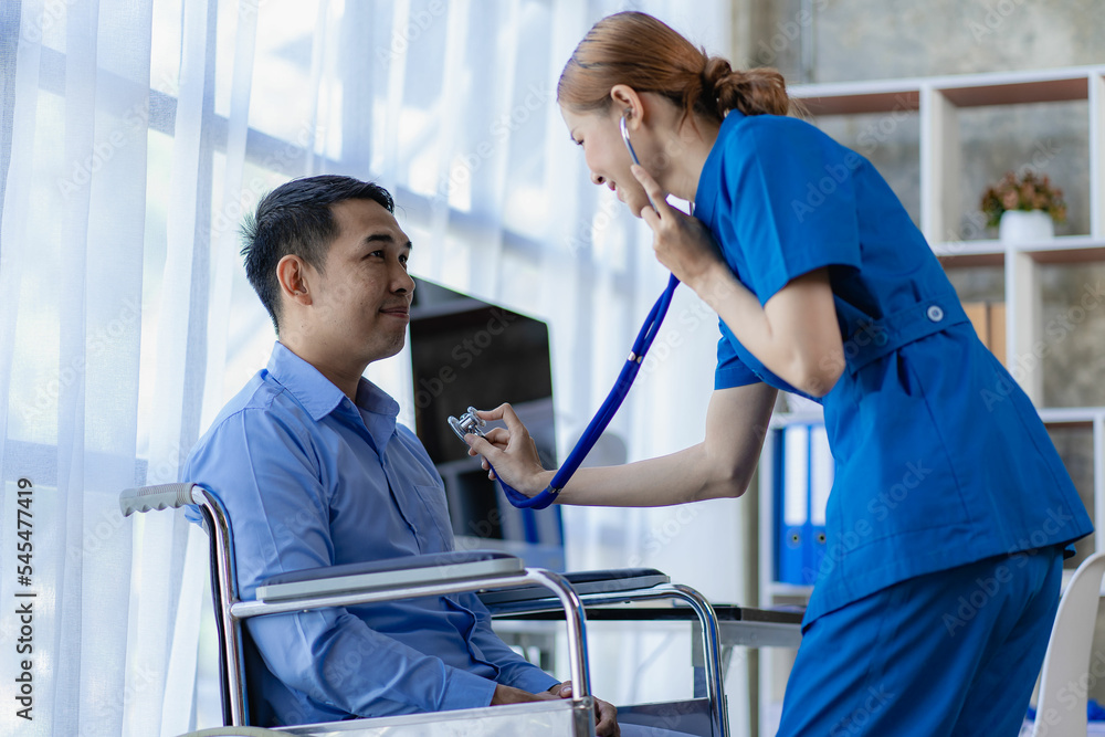 Asian female doctor using a stethoscope to examine a male patient's heart rate Doctor checking patient's respiratory rate or pulse rate by using stethoscope Asian female doctor using a stethoscope to examine a male patient's heart rate Doctor checking patient's respiratory rate or pulse rate by using stethoscope