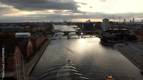 Drone shot over a canal near water towards bridge in Copenhagen at sunset