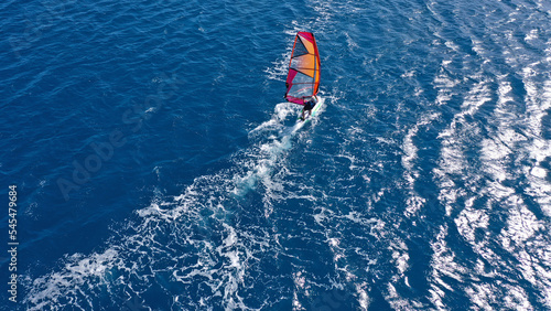 Aerial frone view photo of fit man practising wind surfing in Mediterranean bay with crystal clear deep blue sea © aerial-drone