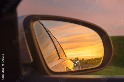 View in the rear view mirror on a road during a very colorful sunset © Frans