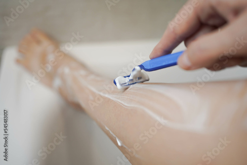 Shave with a razor. Shaving legs with a disposable razor in the shower. Removal of unwanted hair. Women s legs without epilation.