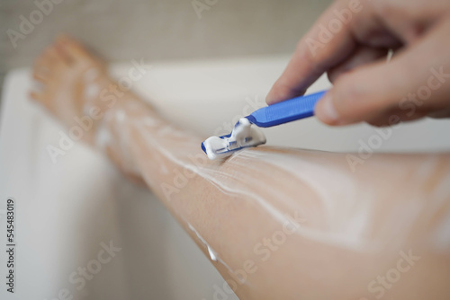 Shave with a razor. Shaving legs with a disposable razor in the shower. Removal of unwanted hair. Women's legs without epilation.
