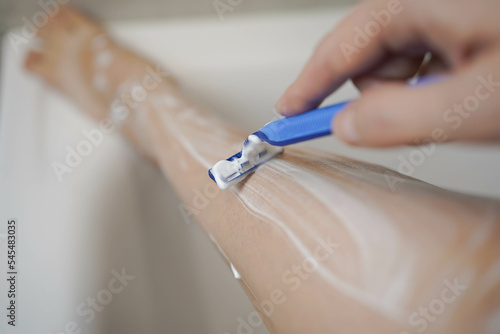 Shave with a razor. Shaving legs with a disposable razor in the shower. Removal of unwanted hair. Women's legs without epilation.