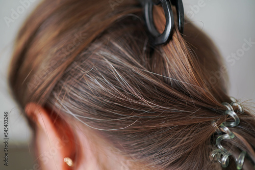 Gray hairs on the head of a young girl. Long gray hair. The initial stage of gray hair. The problem of gray hair in women.