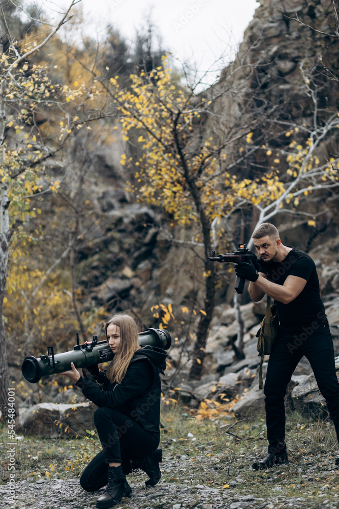 Fototapeta premium Guy and girl in military with bazooka and machine guns pose for camera