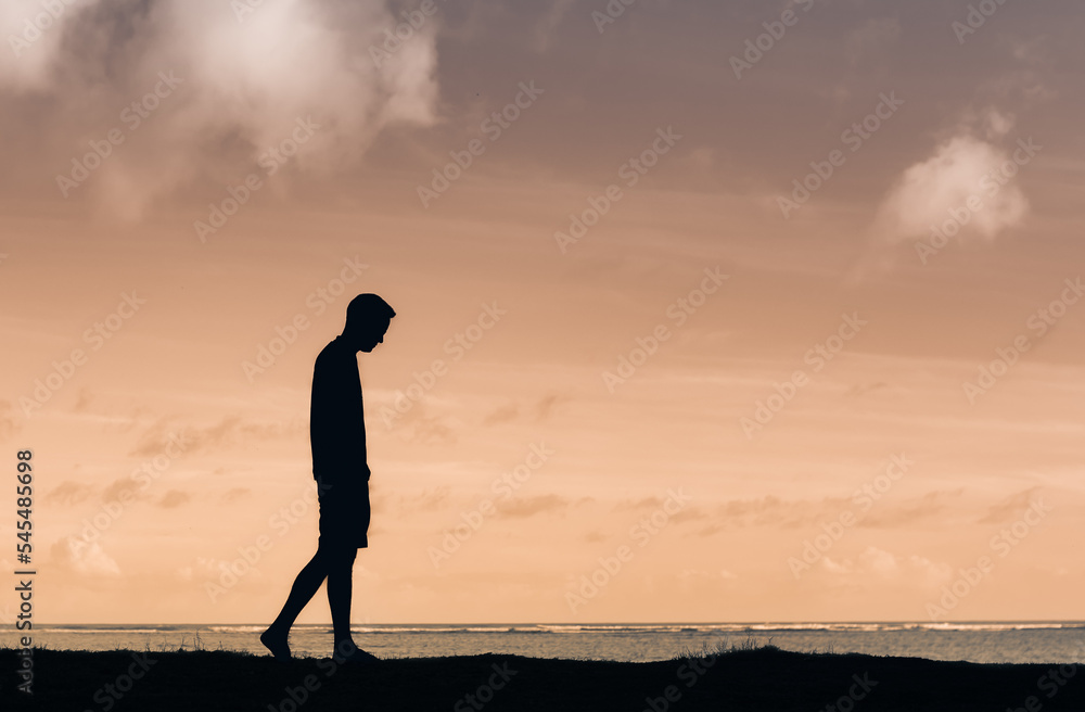 Young thoughtful male silhouette walking alone outdoors thinking 