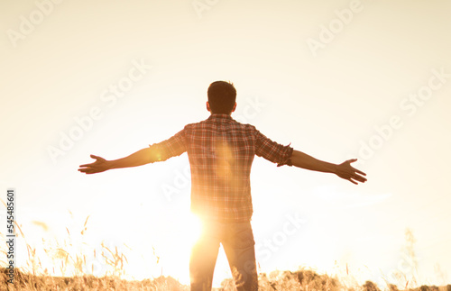Young man with hands up the morning sun light finding happiness, peace and hope in nature 