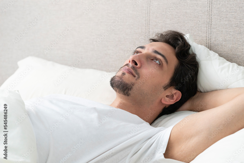 Thoughtful handsome man lying in the bed at the early morning Thoughtful handsome man lying in the bed at the early morning