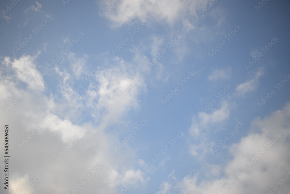 Obraz premium ays of the sun through cirrus clouds against a blue sky, white rainy clouds against a blue sky illuminated by the rays of the sun 