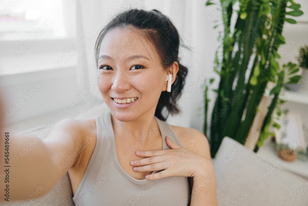 Asian woman blogger filming herself and smiling with headphones, freelance work from home, recording sports workout lifestyle Asian woman blogger filming herself and smiling with headphones, freelance work from home, recording sports workout lifestyle