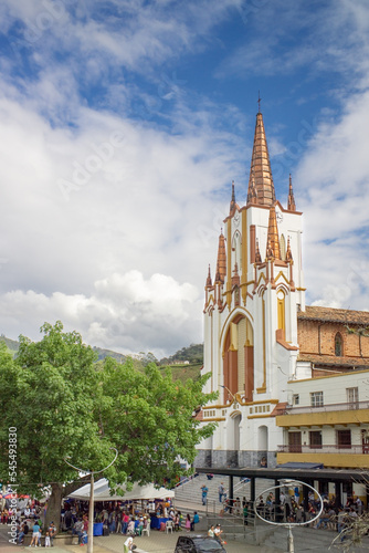 very tall neo-gothic church, white and gold, by day in a square