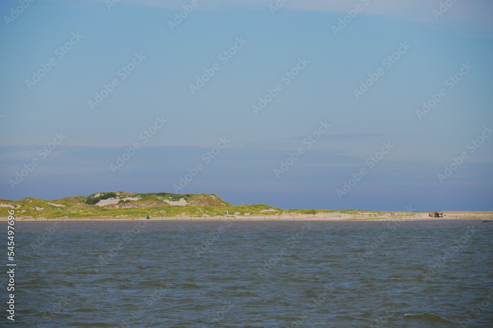 View of the dunes with a sandy beach on the North Sea island of Norderney with a shipwreck on the shore