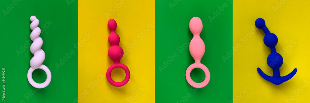 Anal toys. Butt plugs on green and yellow background. Sex toys