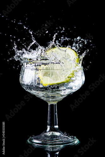 A slice of lemon making a splash in a glass of alcohol (ID: 545503081)