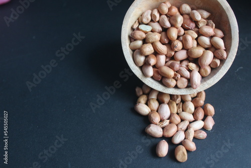 raw peanuts in wooden bowl and black background photo