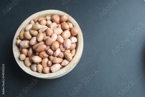 raw peanuts in wooden bowl and black background photo