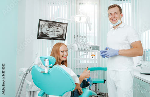 Doctor dentist and young woman patient smiling in dental clinic with medical equipment, x-ray dental, tools. Smile healthy teeth concept