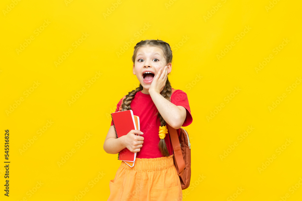 A schoolgirl with a satchel is getting ready to go to school. Children's education. Preparatory courses for schoolchildren. Additional classes for successful exams. Yellow isolated background. A schoolgirl with a satchel is getting ready to go to school. Children's education. Preparatory courses for schoolchildren. Additional classes for successful exams. Yellow isolated background.